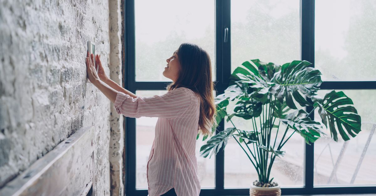 A person adjusting a smart thermostat
