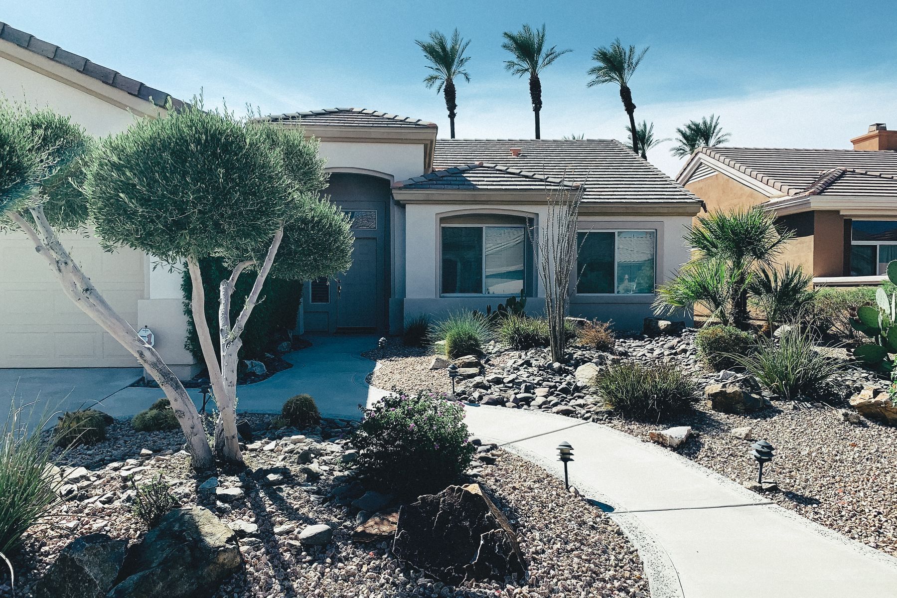 A finished Phoenix desert front yard with decomposed-granite gravel, a dry creek bed, and palms